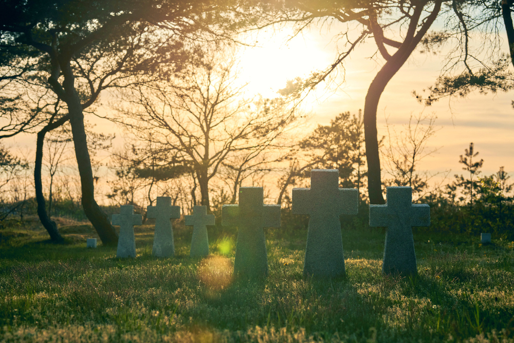 Kreuze auf einem Friedhof im Sonnenuntergang. / iStock/TRAVELARIUM Kreuze auf einem Friedhof im Sonnenuntergang.